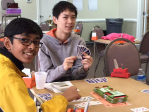 [Two students sitting around table playing Bridge.]